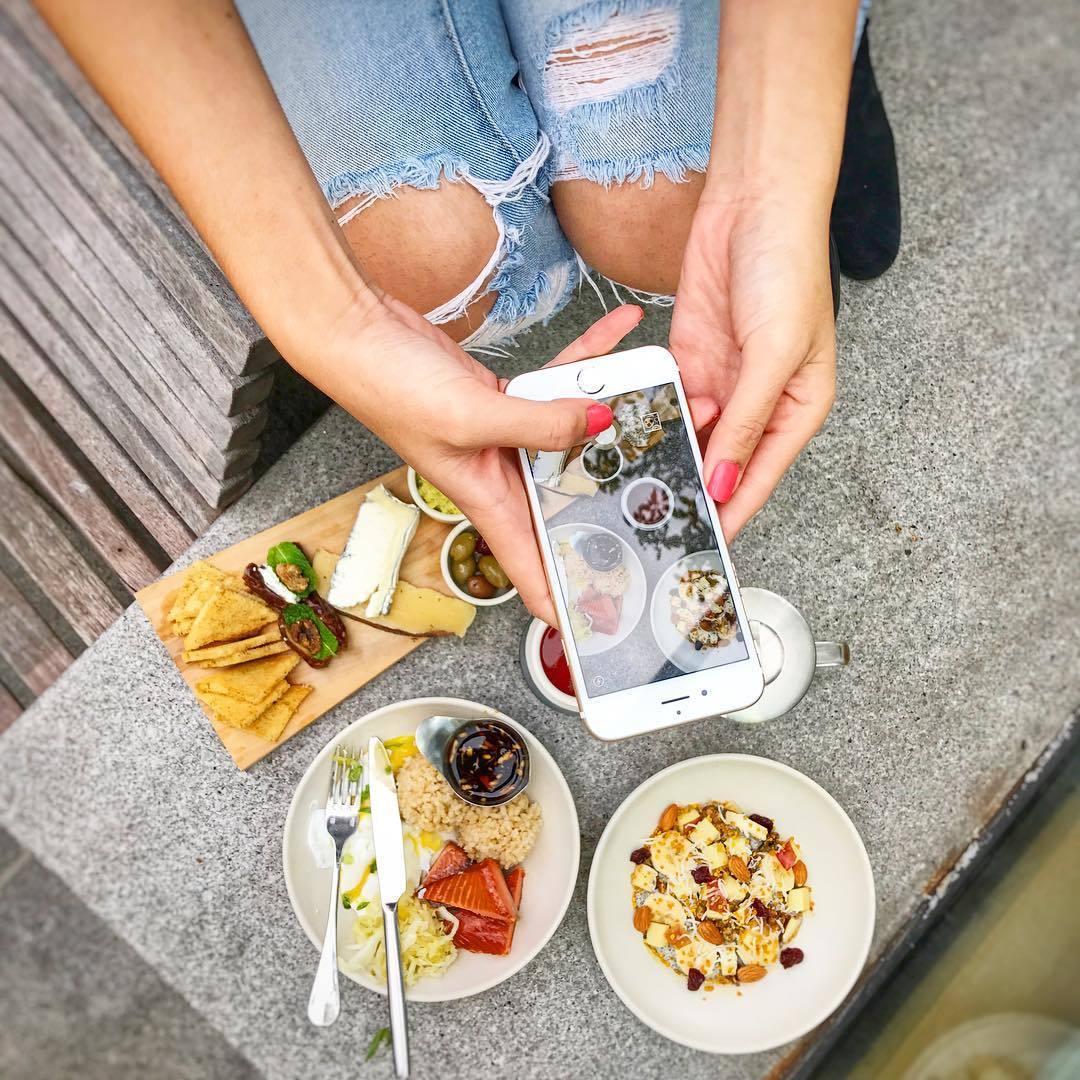 Overhead shot of iPhone taking photo of food dishes on table